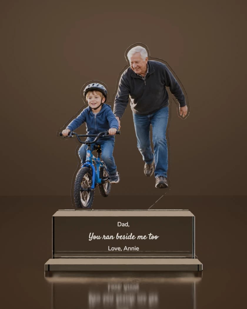 Render of an Ovvie: a grandfather runs beside a boy on a bike, in clear glass. On the base, in white lettering: "Dad," "You ran beside me too" and "Love, Annie".
